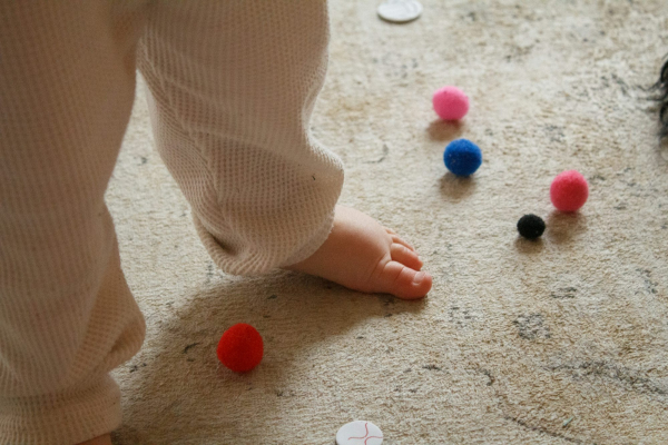 A baby standing on the floor surrounded by buttons