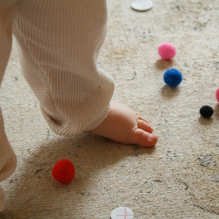A baby standing on the floor surrounded by buttons