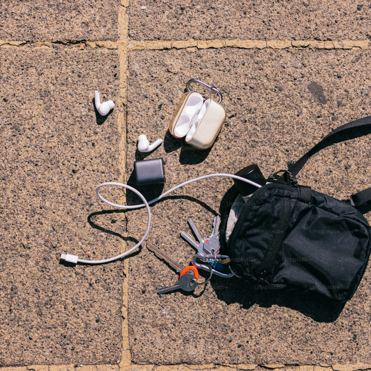 A backpack headphones and a pair of shoes on the ground