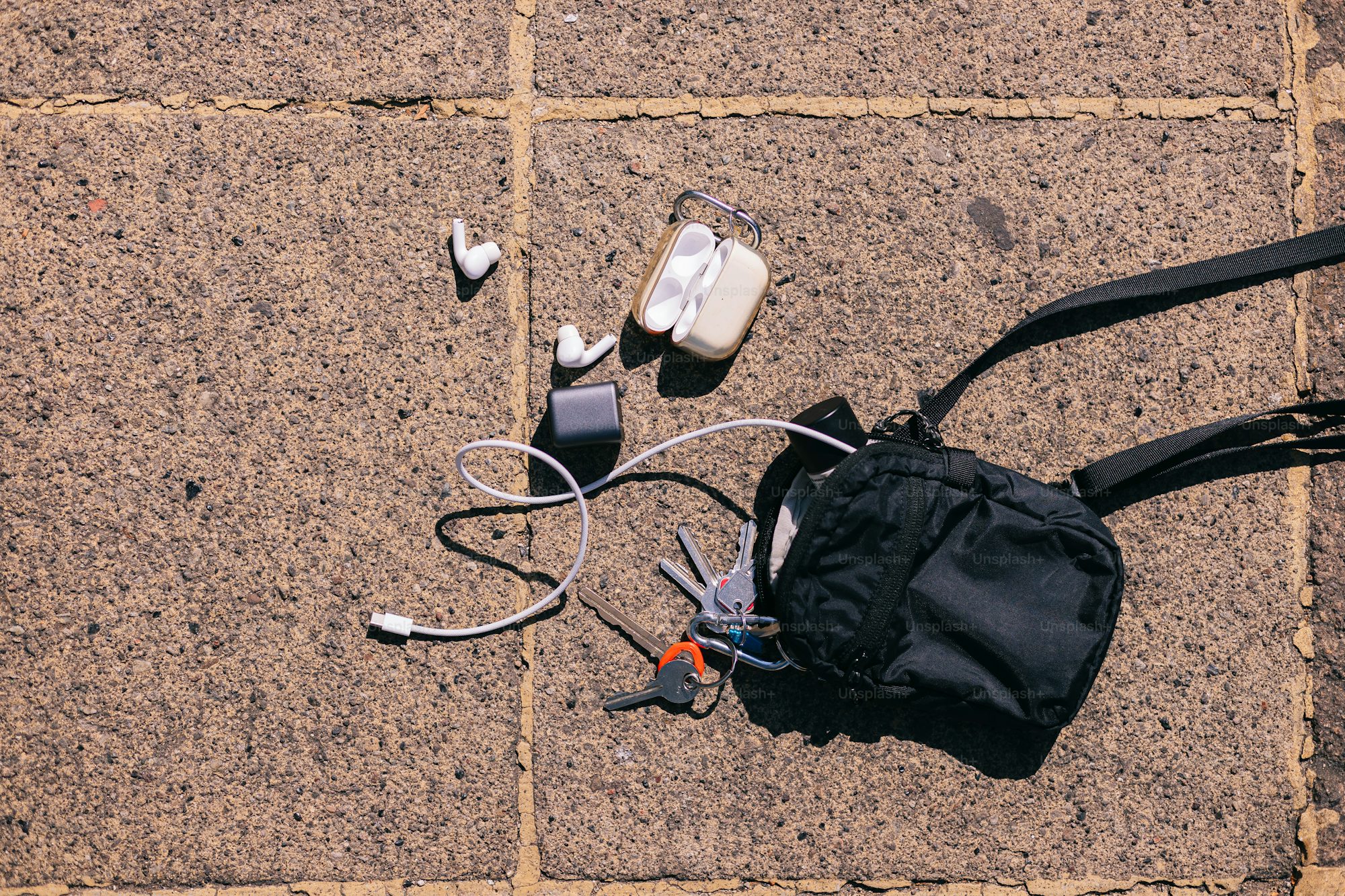 A backpack headphones and a pair of shoes on the ground