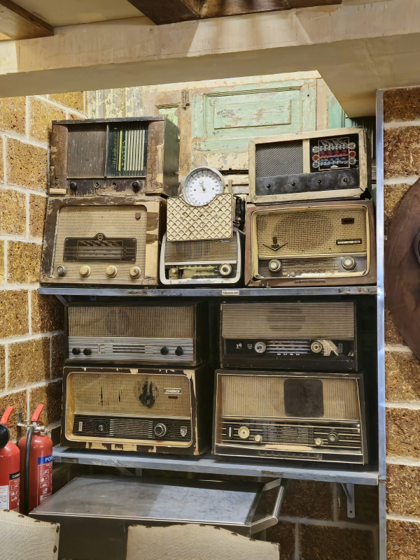 A bunch of old radios are stacked on a shelf