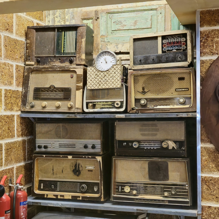 A bunch of old radios are stacked on a shelf