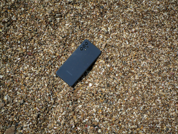 A cell phone laying on the ground covered in sand