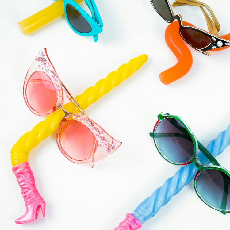 A group of four different colored sunglasses on a white surface