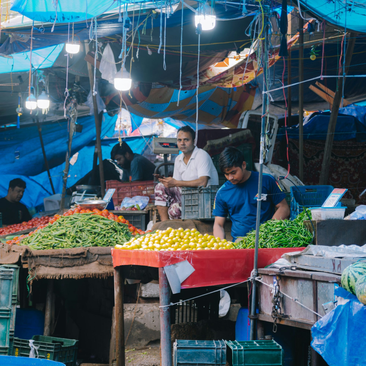 A group of people standing around a fruit and vegetable market