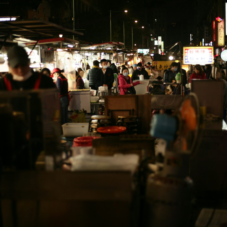 A group of people walking around a market at night