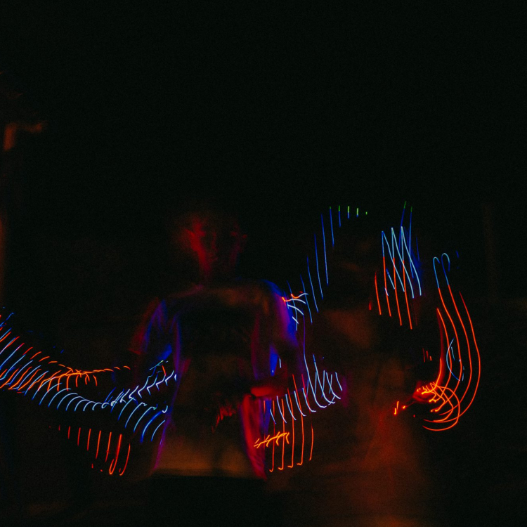 A man standing in the dark with his arms spread out