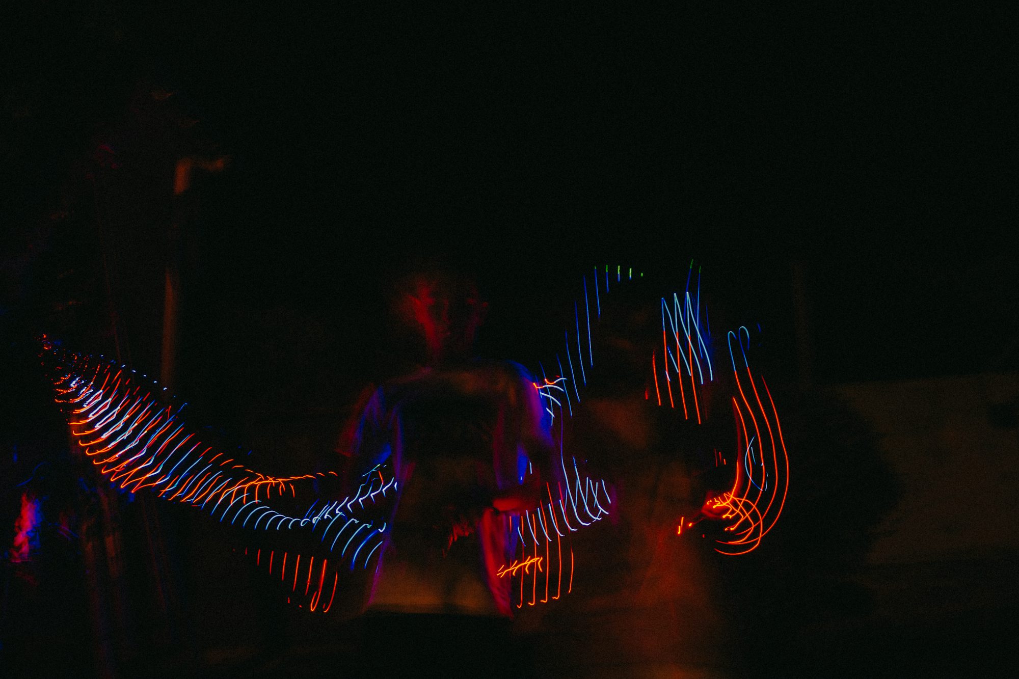 A man standing in the dark with his arms spread out