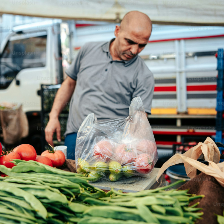 A man standing next to a pile of vegetables