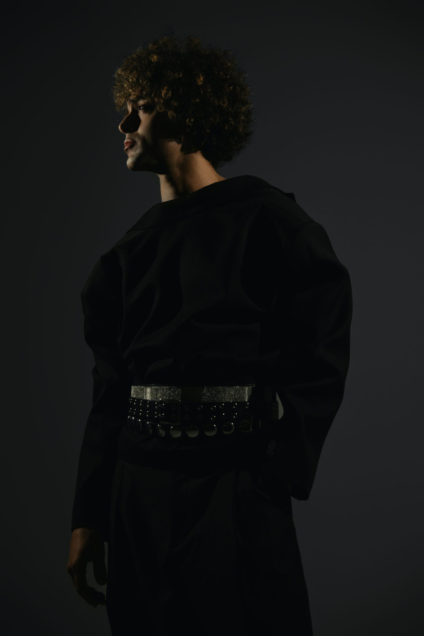 A man with curly hair wearing a black outfit