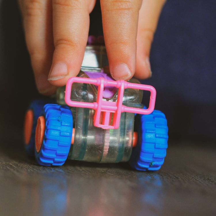 A person holding a toy car on top of a table