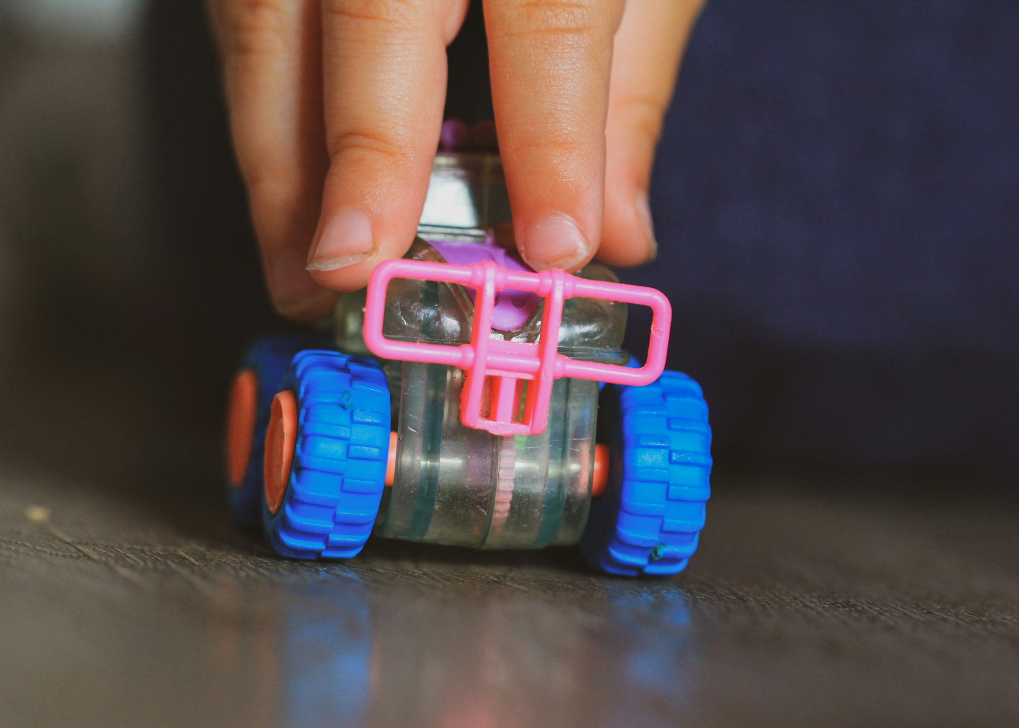 A person holding a toy car on top of a table