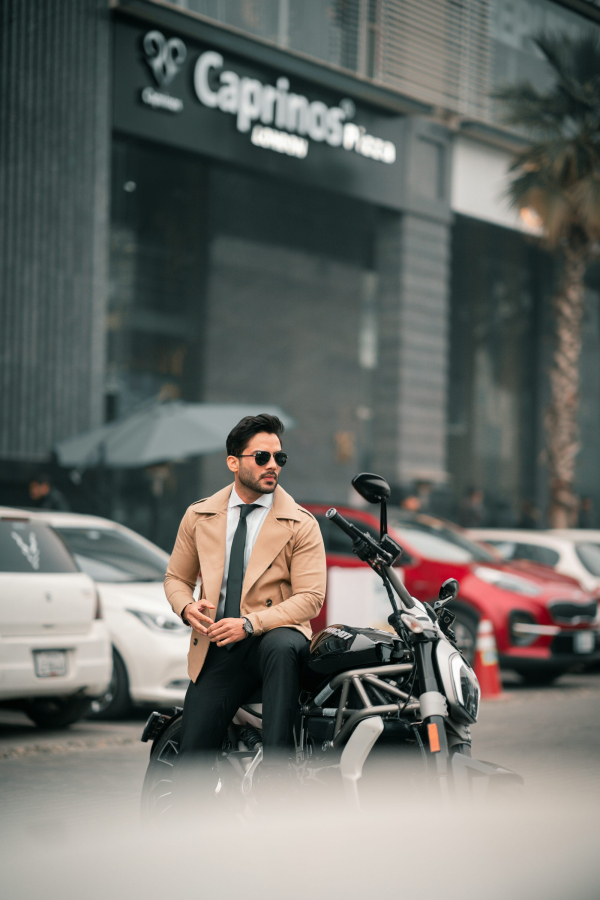 A stylish man sits on a motorcycle