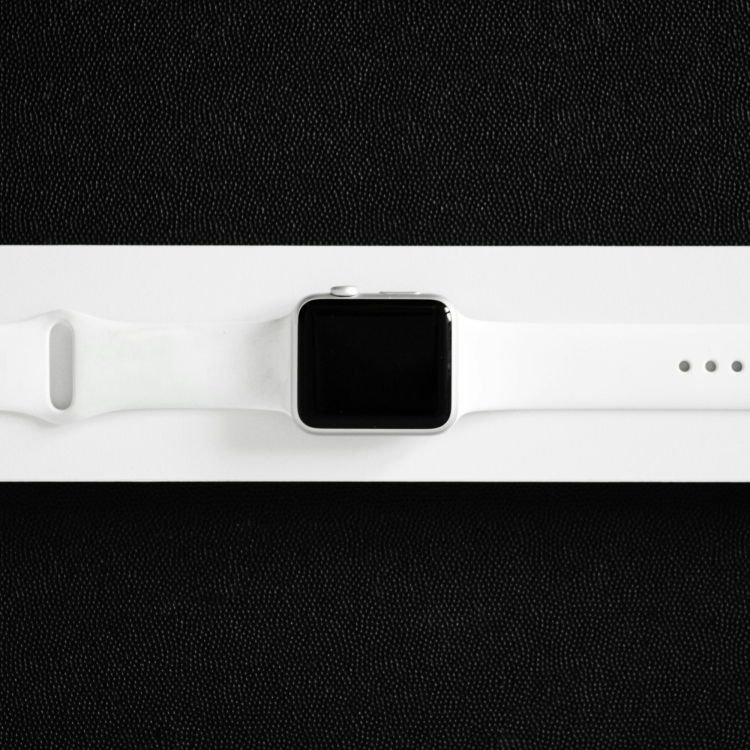 A white apple watch sitting on top of a black surface