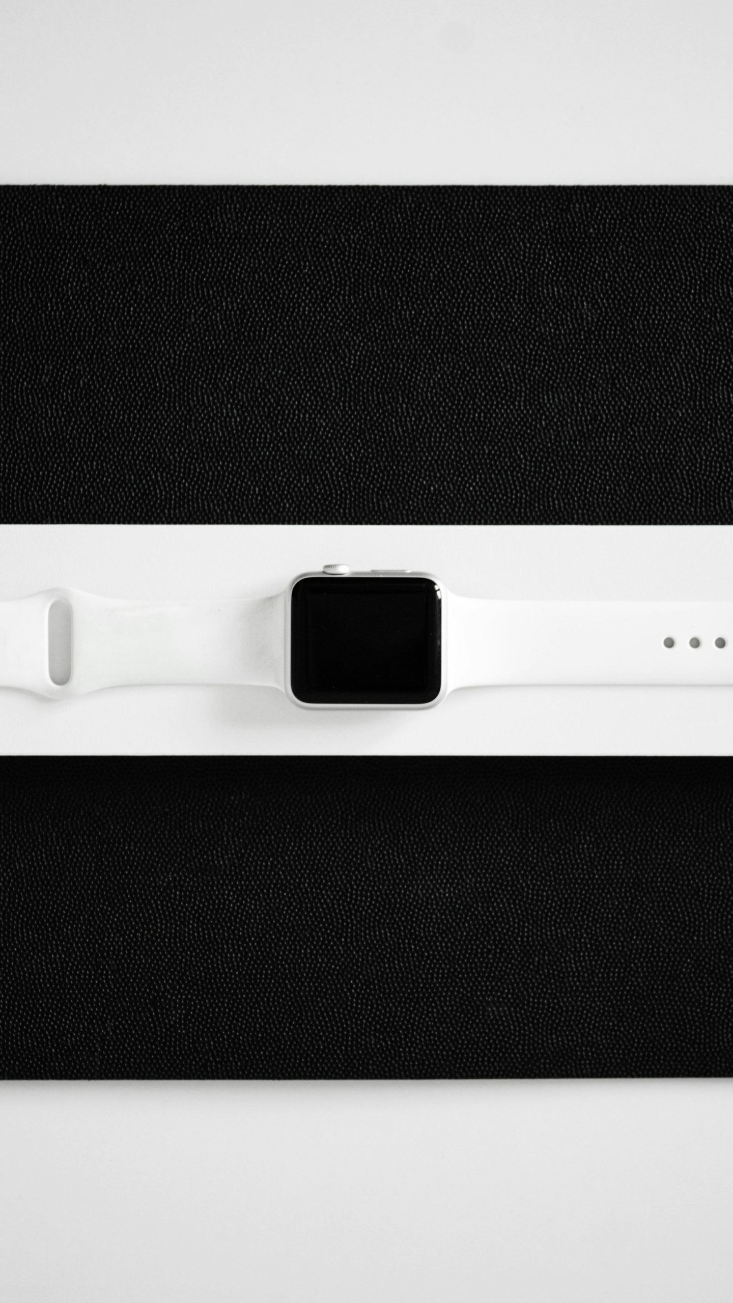 A white apple watch sitting on top of a black surface