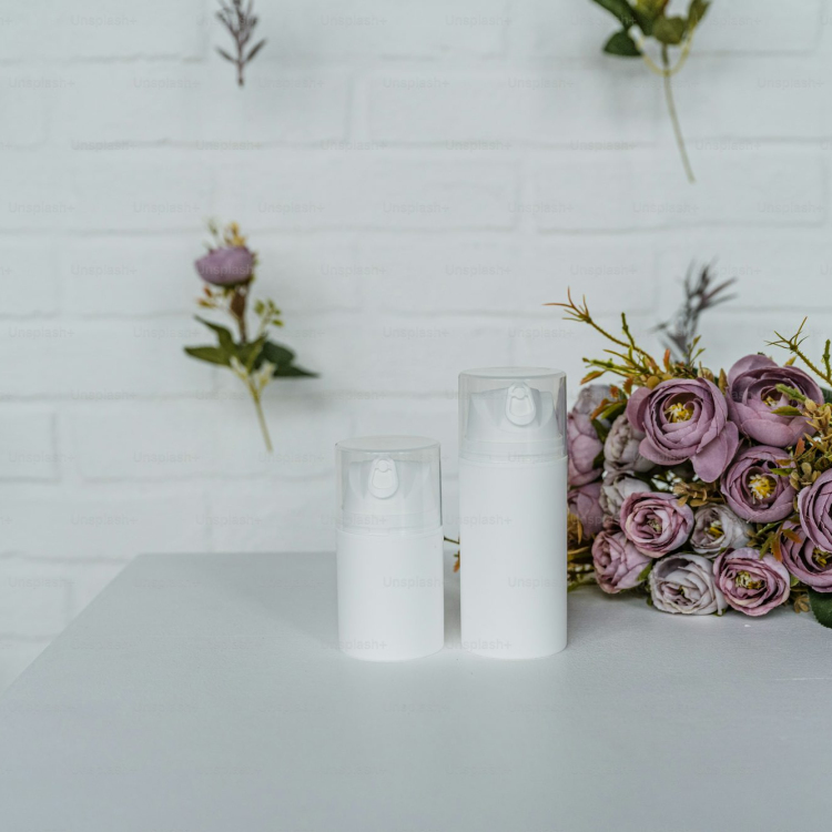 A white table topped with two bottles of lotion next to a bouquet of flowers