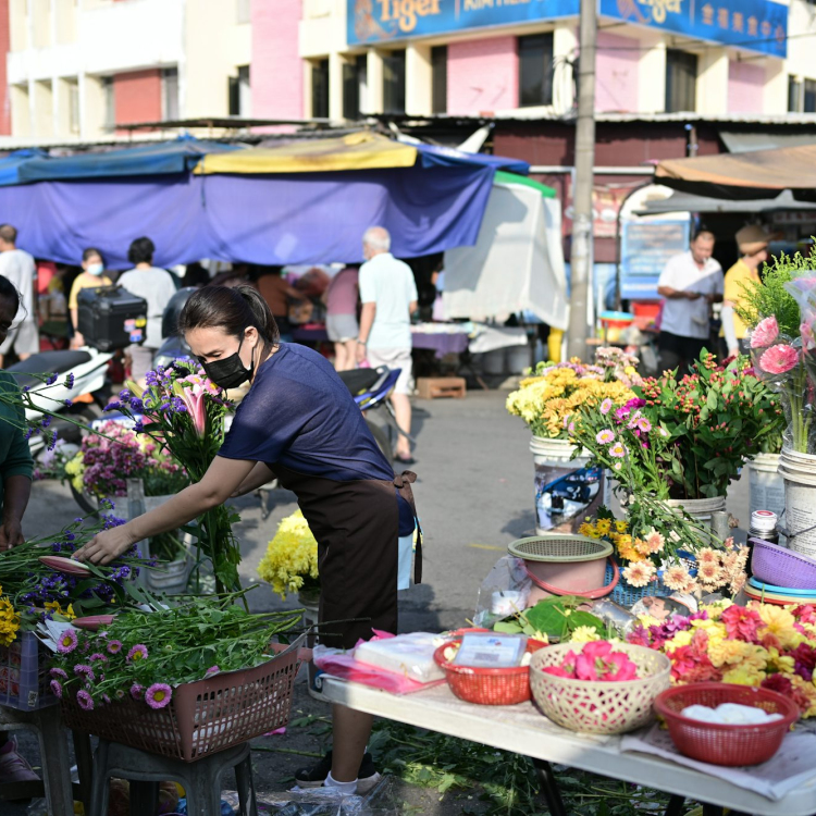 A woman arranges flowers in a bustling outdoor market