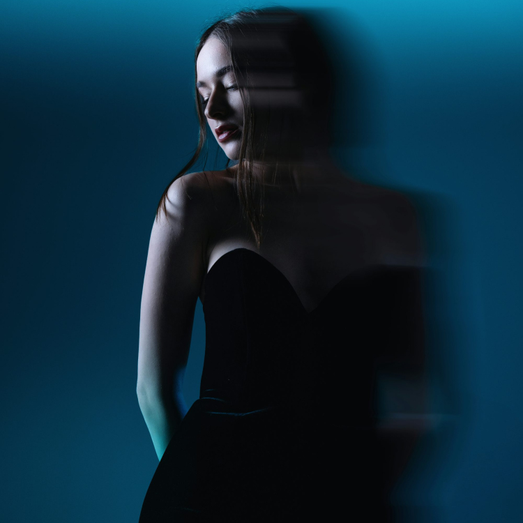 A woman in a black dress standing in front of a blue wall