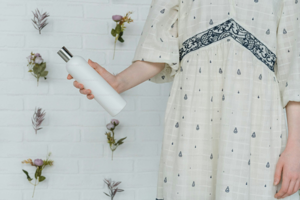 A woman in a white dress holding a white bottle
