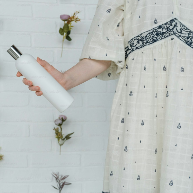 A woman in a white dress holding a white bottle