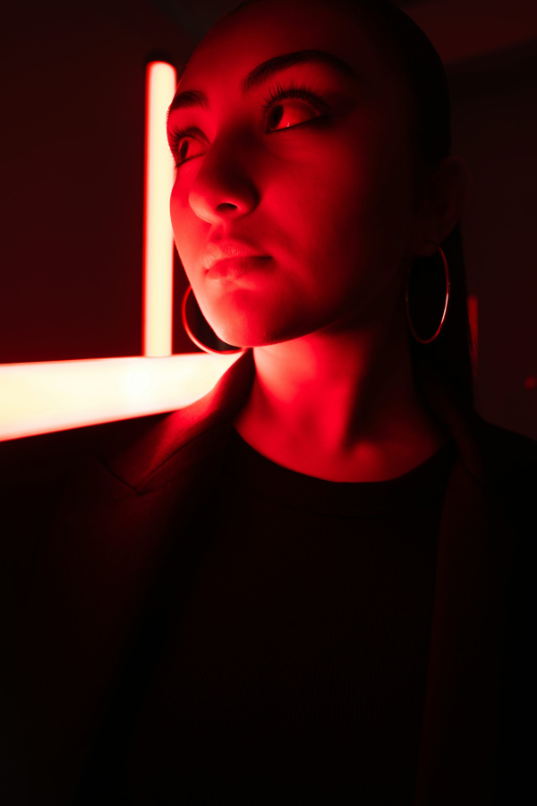 A woman is lit dramatically by red lights