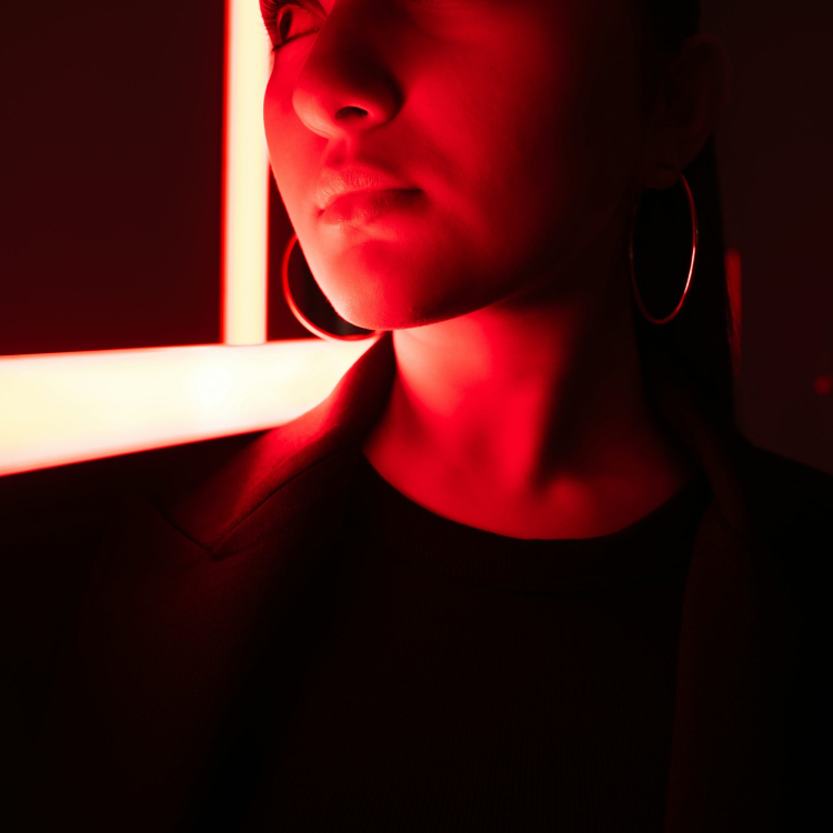 A woman is lit dramatically by red lights