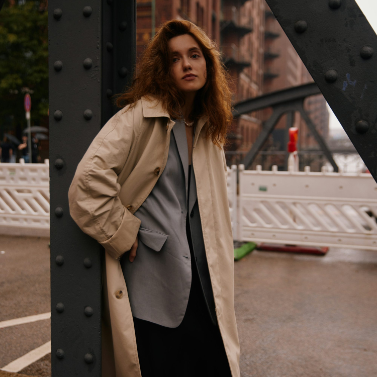 A woman leaning against a metal structure in a city