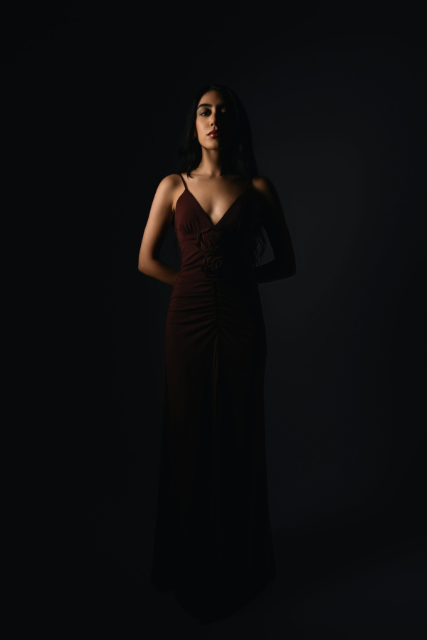 A woman stands confidently in the darkness