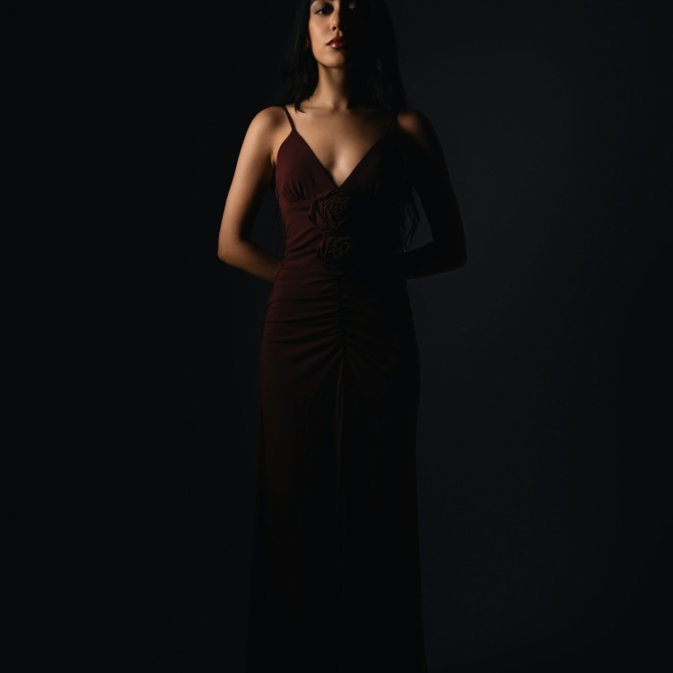 A woman stands confidently in the darkness