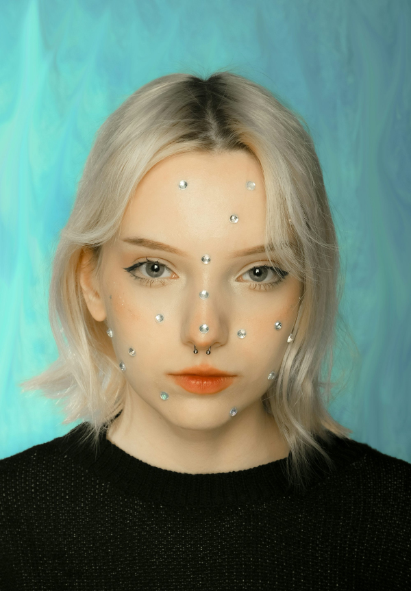 A woman with white hair and pearls on her face