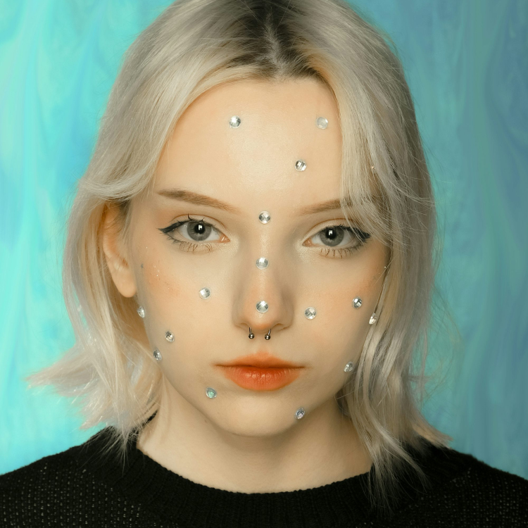 A woman with white hair and pearls on her face