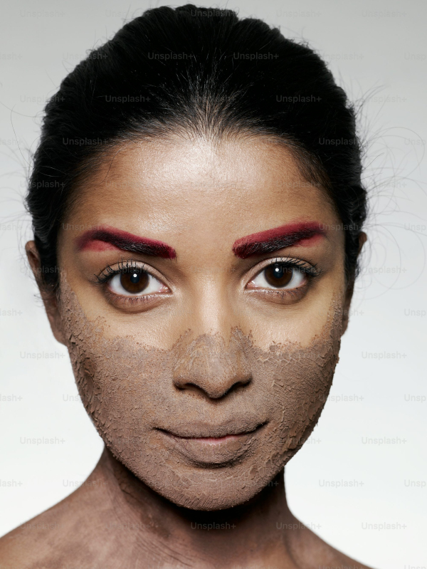 A womans face is covered in clay