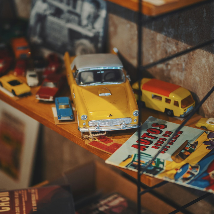 A yellow toy car sitting on top of a wooden shelf