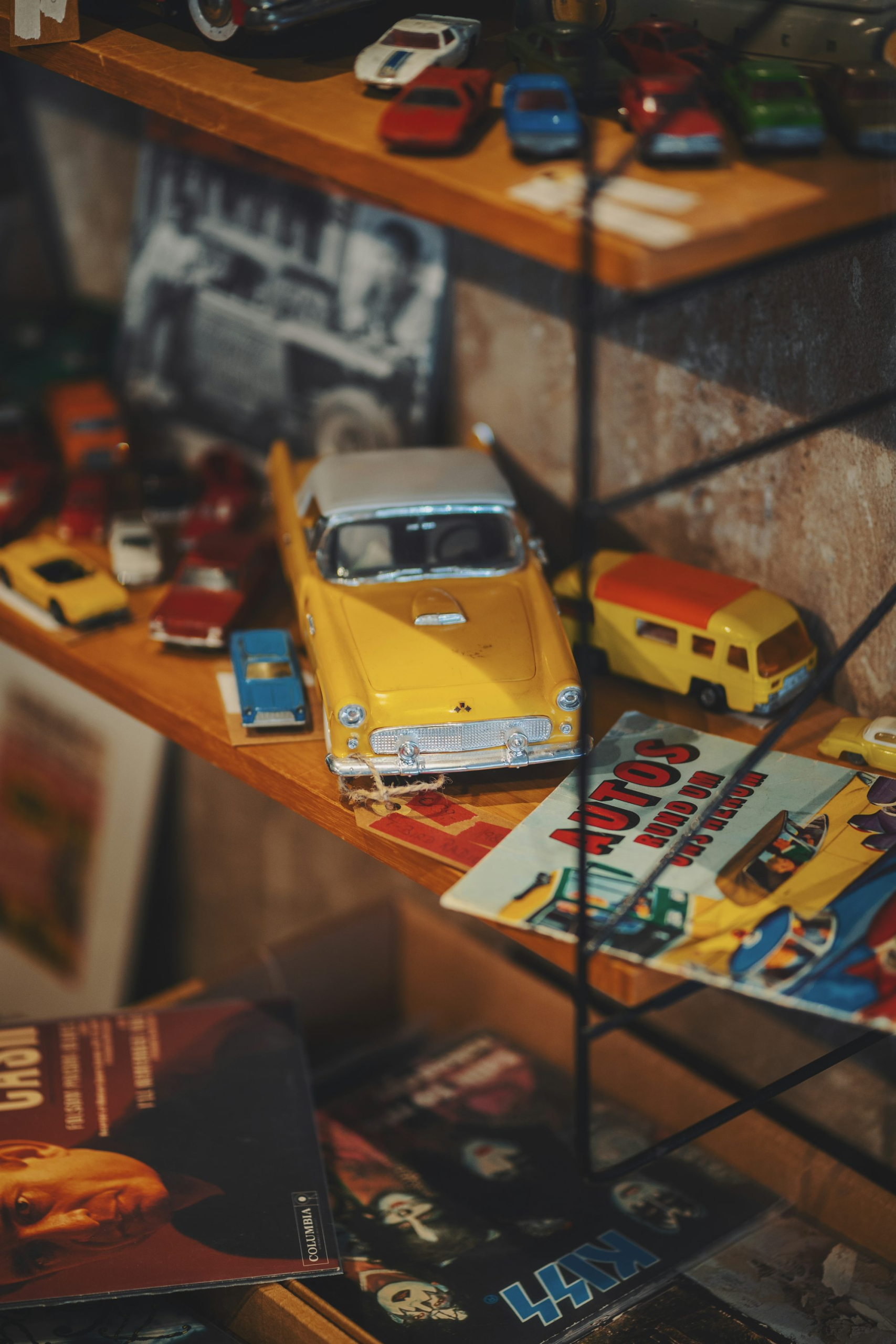 A yellow toy car sitting on top of a wooden shelf