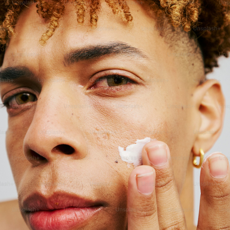 A young man is shaving his face with a cotton pad