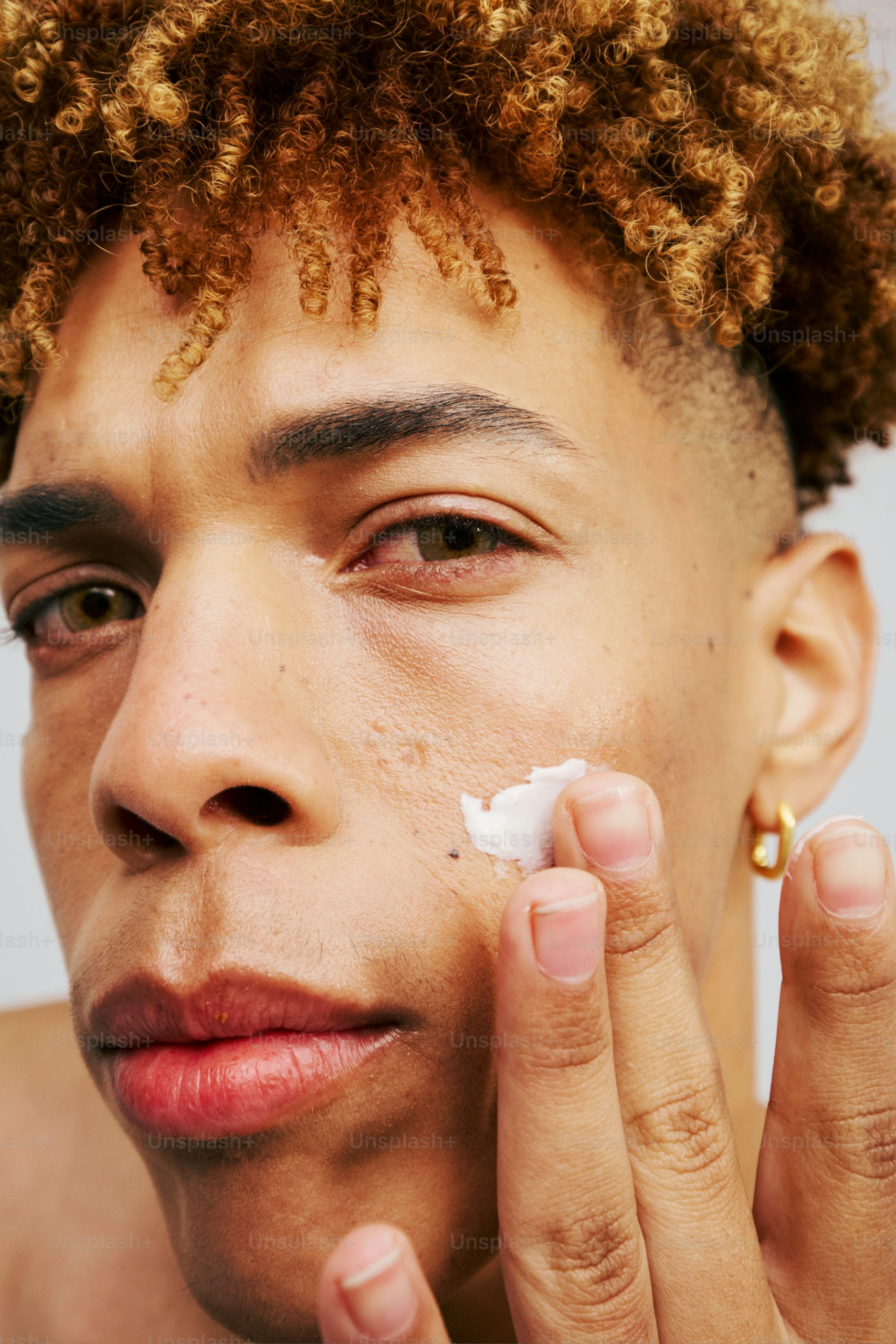 A young man is shaving his face with a cotton pad