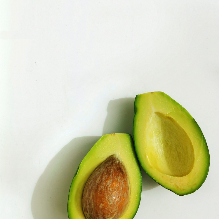 An avocado cut in half on a white surface