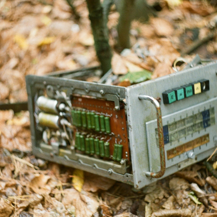 An old radio sitting on the ground in the woods