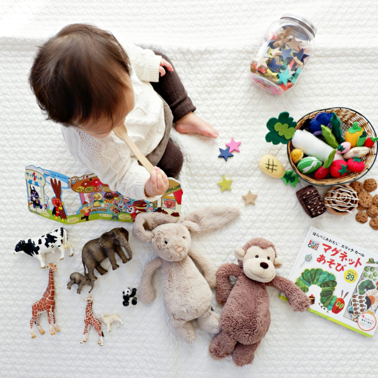 Boy sitting on white cloth surrounded by toys