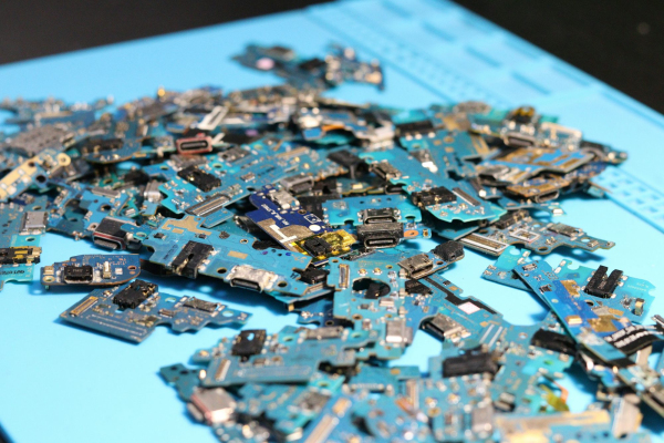 Electronic circuit boards are piled on a blue mat