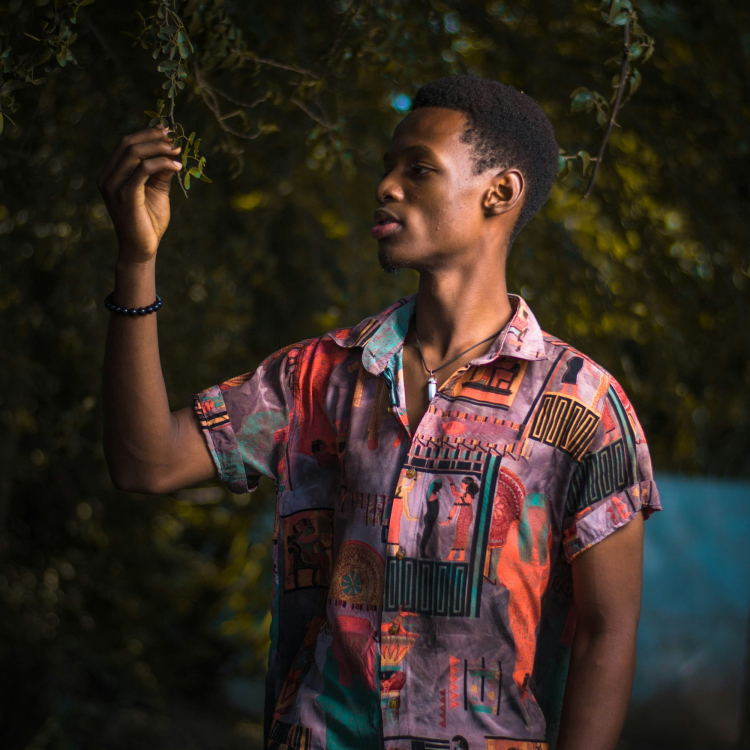 Man in blue and red button up shirt standing and holding his face