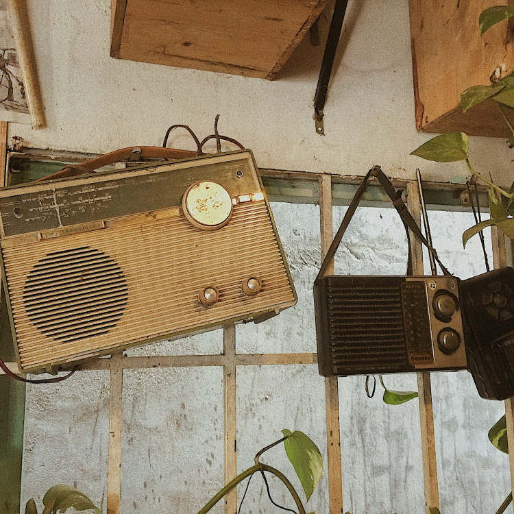 Three assorted-color radios hang on wall