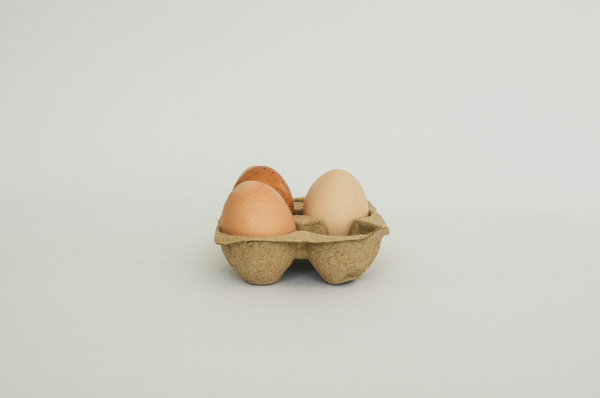 Three eggs in a carton on a white background