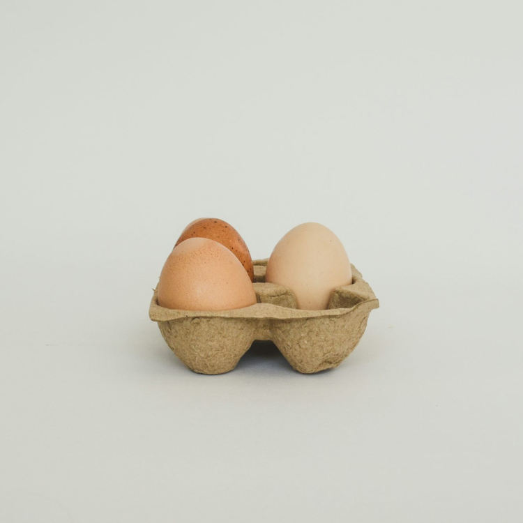 Three eggs in a carton on a white background