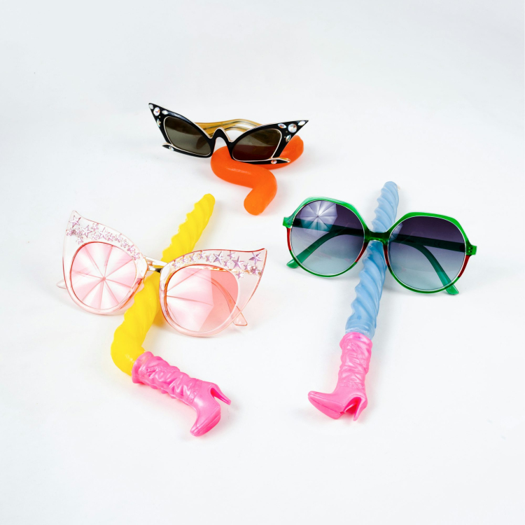 Three pairs of sunglasses and a toothbrush on a white background