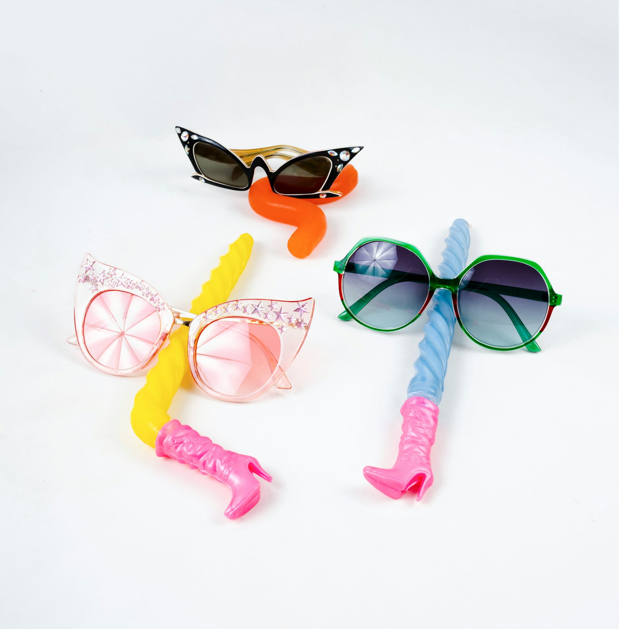 Three pairs of sunglasses and a toothbrush on a white background