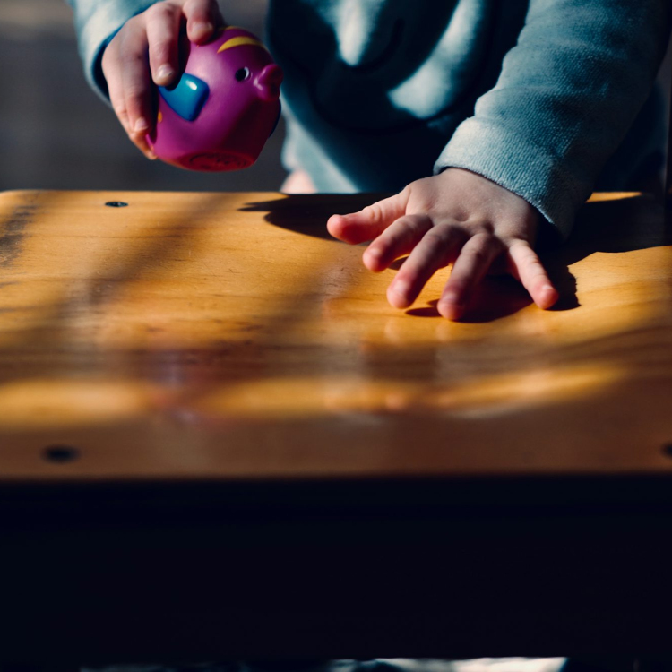 Toddler playing on table while holding purple ball