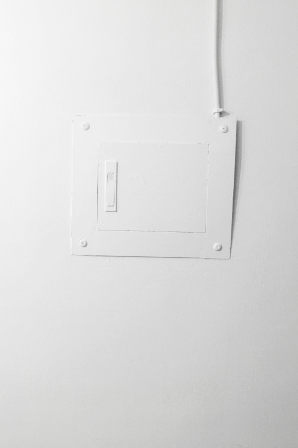 White electric switch mounted on white painted wall