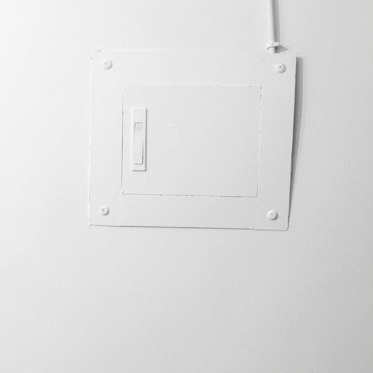 White electric switch mounted on white painted wall